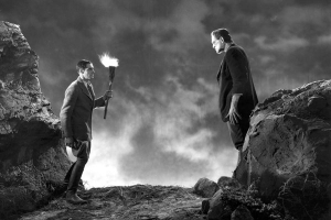 one man with a torch confronts the creature while standing outside on top of a bluff