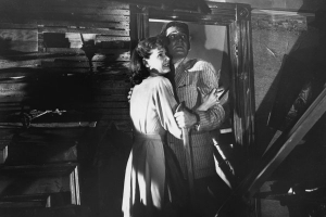 a man and a woman embracing with fear in a torn down room